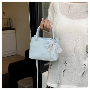 Close-up of light blue leather bucket bag with lace pearl bow and fashion logo