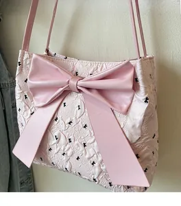 Close-up of pink tote bag with large bow detail and black K letter embroidery pattern