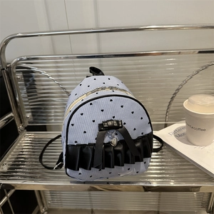 Striped mini backpack with black bow and heart pattern on a decorative display stand