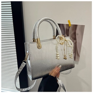 Close-up of silver leather square bag with pearl bow charm and dual top handles