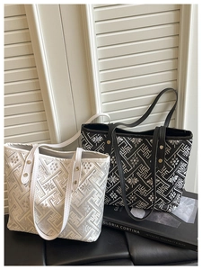 Detailed embroidery texture on black and white tote bags with elegant gold rivets