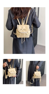 Detail of off-white PU leather mini backpack with lace trim, bows, and drawstring design