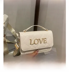 Detail of cream quilted crossbody bag with gold metal LOVE lettering and wide strap