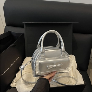 Silver metallic bowling handbag with leather bow and lace trim on a satin background