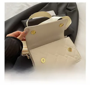 Detail view of the white quilted crossbody bag showing gold magnetic closure and interior