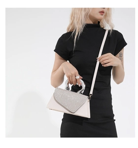Detail of glittery crossbody bag with silver circular metal handle and cream leather strap