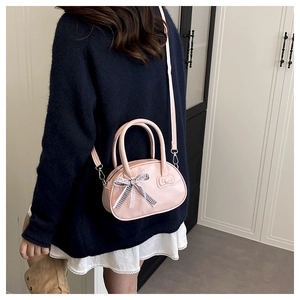 Pink mini boston bag with bow detail and adjustable strap shown on model profile