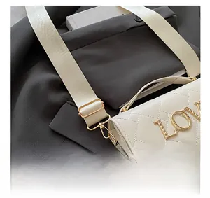 Detailed view of the adjustable wide shoulder strap on a quilted white crossbody bag
