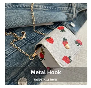 Detailed view of strawberry print mini bag with golden metal chain and spring hook
