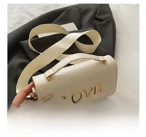 Detailed view of the off-white quilted bag with large gold LOVE metal buckle and wide strap