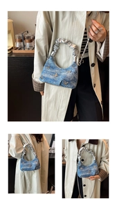 Detailed macro view of denim shoulder bag with butterfly charms and silver ruched handle