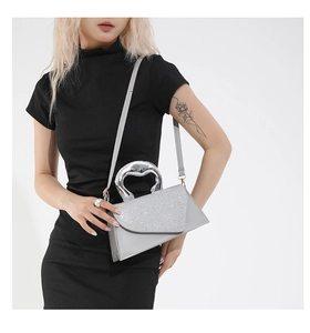 Detail of silver sequined handbag featuring a unique metallic irregular top handle