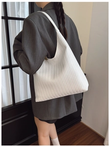 Detail of white woven tote bag showing chevron pattern texture and minimalist shoulder strap