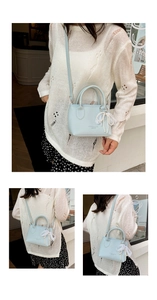 Detailed view of mint blue mini bucket bag with lace bow, pearl charm, and lychee texture