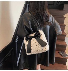 Quilted white shoulder bag with black bear print and large leather bow on model