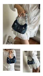 Detail of blue denim butterfly handbag featuring silver metal charms and chain strap