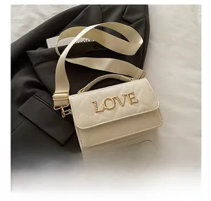 Detailed macro view of quilted cream leather bag with gold LOVE hardware and wide strap