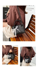 Detail of black pebbled leather mini bag featuring lace bow and pearl charm ornament