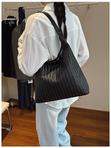 Detail shot of a black woven tote bag showing the texture and large capacity fit