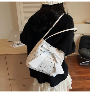 Close-up of a white tote bag with black bow embroidery and a large 3D bow accent