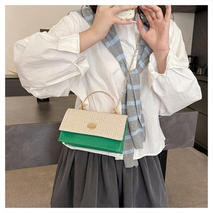 Dettaglio borsa intrecciata verde e beige con manico ad anello dorato e tracolla