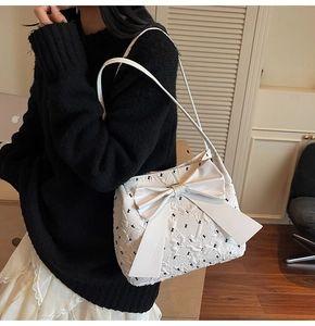 Detail view of a white bow shoulder bag with black butterfly prints worn by a model