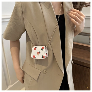 Detailed view of mini cherry print wallet with gold chain strap on casual blazer