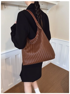 Sac cabas tissé marron porté à l'épaule montrant la capacité et la texture tressée