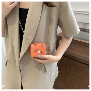 Mini orange lychee leather bag with strawberry prints and golden chain strap detail