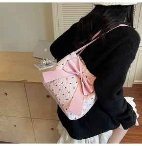 Detailed view of pink quilted tote bag with black bow patterns and large silk bow ornament