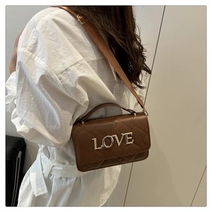 Detailed view of dark brown quilted crossbody bag featuring a golden LOVE logo and wide strap