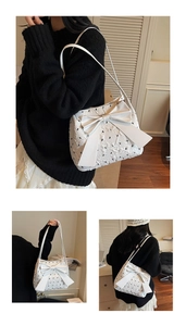 Detail of white seersucker shoulder bag featuring a large bow and black floral embroidery