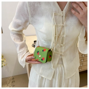 Detailed shot of mini crossbody bag with red strawberry print and gold chain strap
