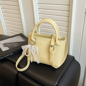 Petit sac seau jaune pâle minimaliste avec breloque nœud en perles sur support noir
