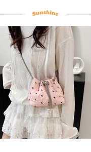 Close-up of pink bucket bag with black bow jacquard, silver chain and pearl charms