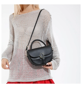 Close-up of black matte leather saddle bag with gold oval buckle and pleated bottom detail