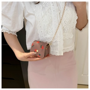 Detailed view of mini strawberry print crossbody bag with gold chain and round buckle
