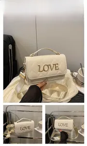 Détail du sac bandoulière blanc matelassé avec lettrage LOVE doré et sangle large