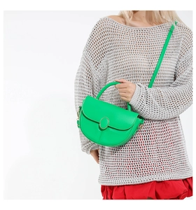 Detail of green saddle bag with gold metal buckle and matte leather texture on model