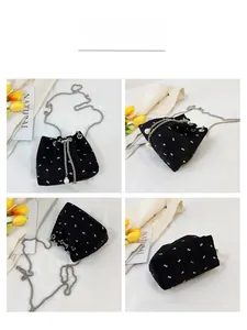 Detail view of black drawstring bucket bag with white butterfly patterns and pearl accent