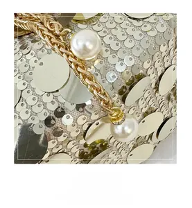 Detail of golden sequin bucket bag with woven metal chain and elegant white pearl accents