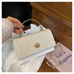 Dettaglio della patta in paglia intrecciata e manico ad anello dorato di borsa beige