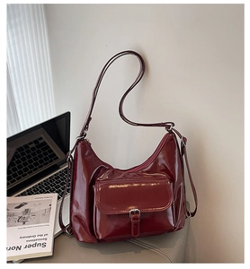 Détail du sac fourre-tout en cuir huilé rouge foncé avec boucle argentée et texture brillante