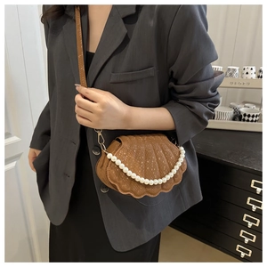 Brown shell-shaped crossbody bag with snake-skin texture and pearl strap on model