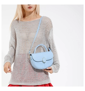 Detail of light blue leather saddle bag with gold metal buckle and adjustable strap