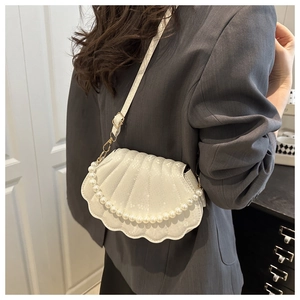Detail of white shell-shaped bag with pearl handle and glossy textured leather finish