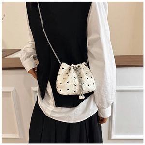 Detail of white bucket bag with black bow prints and large pearl drawstring accents