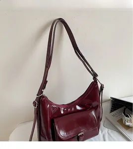 Detail of burgundy patent leather tote with silver buckle and smooth adjustable strap