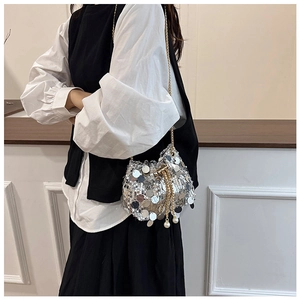 Sac seau à paillettes argentées avec chaîne dorée et glands en perles sur modèle