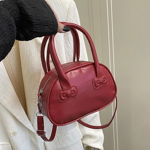 Red bow bowling handbag with detachable strap held by model for casual fashion look